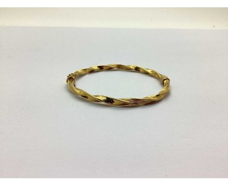 A Modern Twist Style Bangle, to sprung hinge with safety clasp, stamped "375" (5.7grams).