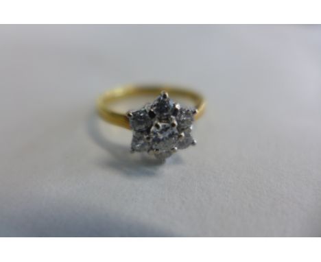 An 18ct yellow and white gold diamond daisy cluster ring, the central brilliant cut diamond is set in six claws and is surrou