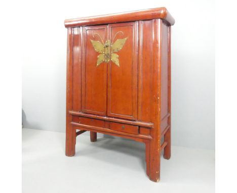 An early 20th century Chinese two-door cabinet of canted form, with applied brass decoration, shelf and drawer fitted interio