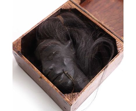 A shrunken head, mid-20th century, a well-modelled skin and animal hair replica shrunken head, with a handmade vintage wooden