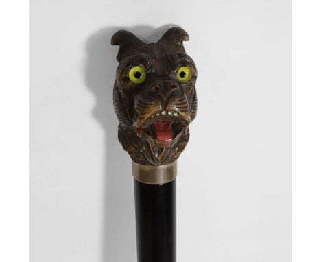 An ebonised walking stick, early 20th century, the handle carved in the manner of a bear or hound, with glass eyes and painte