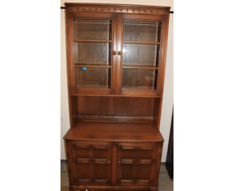 An Ercol dresser enclosed by a pair of glazed doors over two panel doors. 38" wide