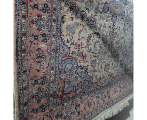A Persian Keshan rug with a floral medallion on a light brown field surrounded by one frieze and two running borders 