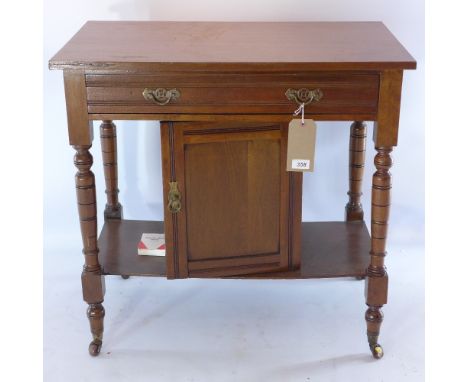 An Edwardian mahogany side table with single drawer above cupboard door and raised on turned legs and castors H 74 x W 77 x D