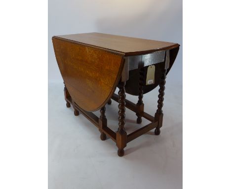 An oak drop leaf table raised on barley twist supports, with bun feet and joined by stretchers, H 74 x W 148 x D 106cm 