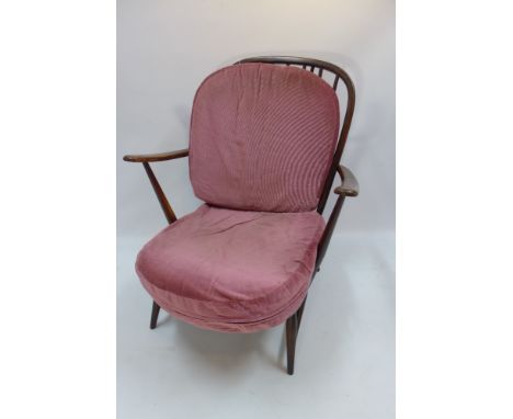 A 1960's Ercol stained beechwood stick back armchair with salmon pink cushions and raised on circular tapered legs, H 88 x W 