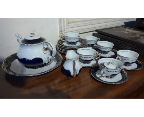 A ZSolnay Hungarian porcelain tea set, on a white ground with cobalt blue borders and gold rims. 