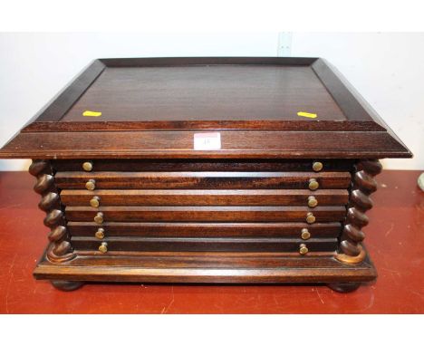 A 20th century stained beech coin collector's cabinet, the six long drawers flanked by barley twist columns, standing on four