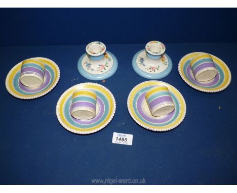 Four Art Deco egg cups and saucers decorated with yellow and blue bands and a pair of hand painted short candle holders stamp