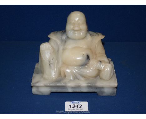 A carved model of a laughing Buddha on a marble plinth, 6'' wide x 5'' tall.