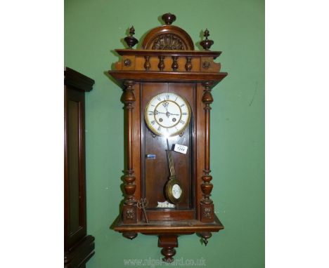 A Mahogany wall clock with enamel face, (pendulum and key present). 31 1/2" x 12 1/2".