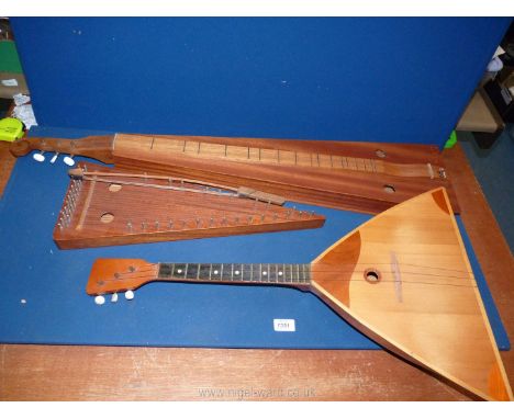 Three wooden instruments including Bowed Psaltery (Zither), Russian Balalaika and one other.