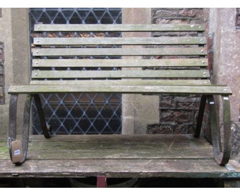 A two seat garden bench with weathered open hardwood slatted seat and combined back raised on a pair of sprung steel supports