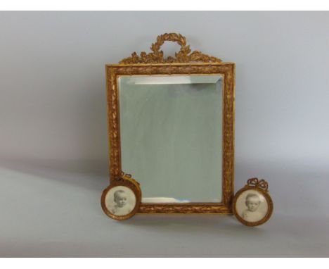 A gilt metal easel mirror with bevel plate, mounted by a wreath; together with two smaller gilt metal picture frames (3)