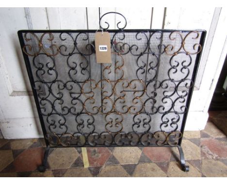 An ironwork fireguard with wire mesh and entwined C scroll panel 