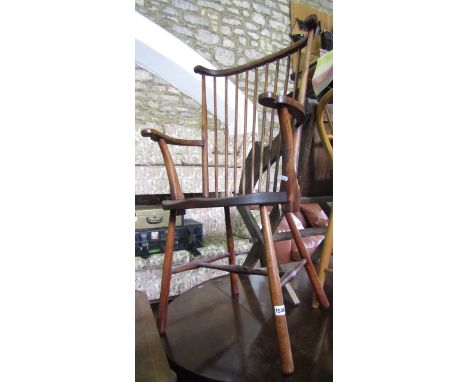 A Windsor style stick back elbow chair with shaped seat on simple turned supports and rails