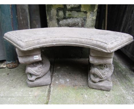 A weathered composition stone three sectional garden bench with curved slab seat raised on a pair of stylised dolphin support