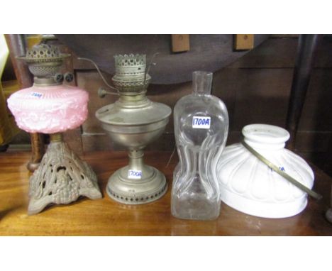 A Victorian oil lamp with cast iron base, pale pink font, further example in chrome with milk glass shade and a waisted hand 