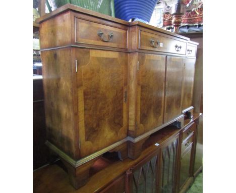 A Georgian style walnut breakfront side cupboard, enclosed by an arrangement of four doors and three drawers with crossbanded