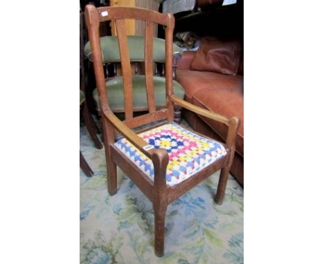 An oak elbow chair with stick back and upholstered seat