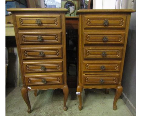 A pair of oak bedside or lamp tables, each fitted with five frieze drawers, with carved and moulded detail and raised on shap