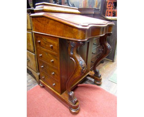 A Victorian figured walnut davenport of four real and four dummy drawers, with carved and shaped cabriole supports, raised st