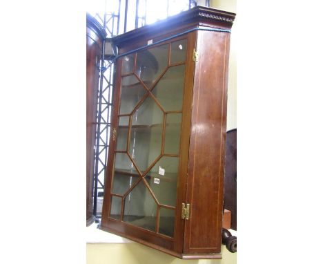 A Georgian mahogany hanging corner cupboard, with astragal glazed panelled door enclosing three shaped shelves with painted i