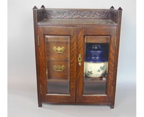 A vintage oak smokers cabinet, the twin glazed doors enclosing a interior fitted with shelves and drawers with a Lambeth toba