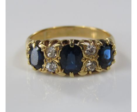 A Victorian gold sapphire and diamond ring, central sapphire 6mm x 4mm approx flanked by twin set diamonds, marks worn, size 
