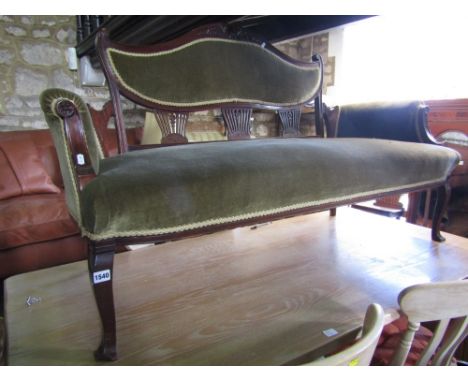 An Edwardian mahogany parlour room sofa with moustache shaped back panel over a pair of scrolled arms, raised on shaped suppo