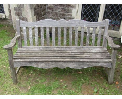 A P J Bridgman & Co Ltd weathered Iroko three seat garden bench, with slatted seat and back beneath an arched rail with acorn