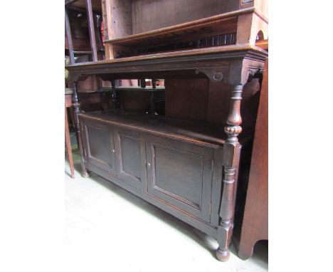 An Edwardian oak buffet, the lower section enclosed by two panelled doors with open centre, the upper shelf surmounted by a f