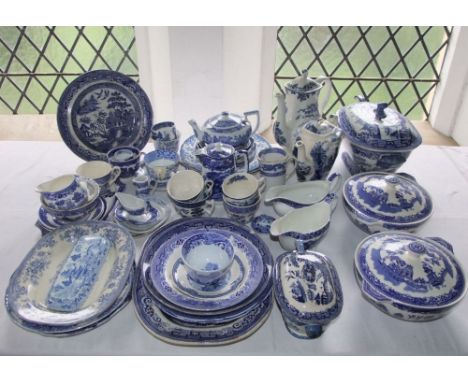 A quantity of blue and white Willow pattern wares including a 19th century tureen and cover and ladle, a further sauce tureen