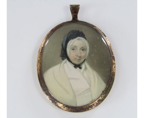 19th century school - bust portrait of a lady in a black bonnet wearing a cream cloak, mounted within a gilt pendant, lock of