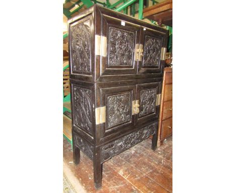 A Chinese hardwood cabinet on three tiers enclosed by two pairs of carved and panelled doors over a lower frieze drawer with 