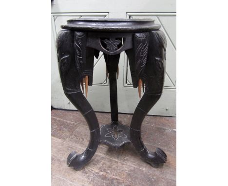 A Chinese jardiniere stand raised on three elephant trunk supports in carved timber with ebonised finish