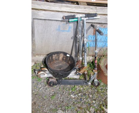 Three children's scooters and a wooden barrel planter.