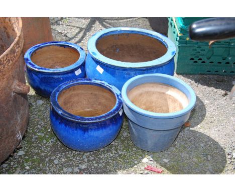 A medium glazed blue planter and three smaller planters.