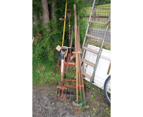 A sack truck, two garden forks and other garden tools.