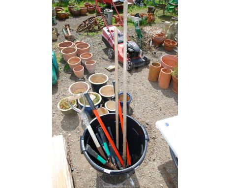 A plastic dustbin of tools, hoe, long arm shears, spade, etc.