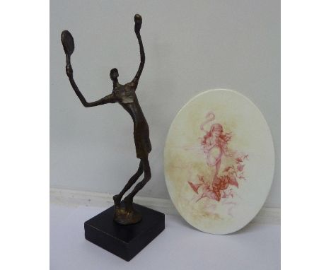 A stylised cast figure of a female tennis player and an oval plaque/stand