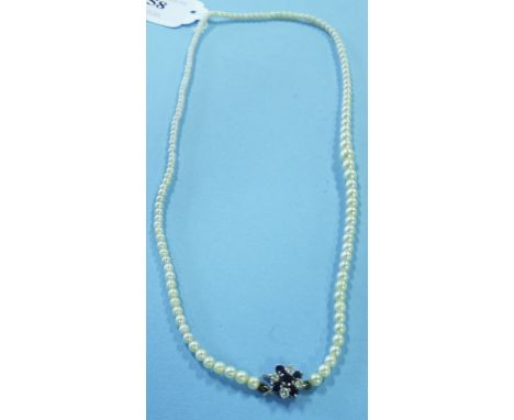 A graduated single strand pearl necklace, with a sapphire and diamond flower head clasp