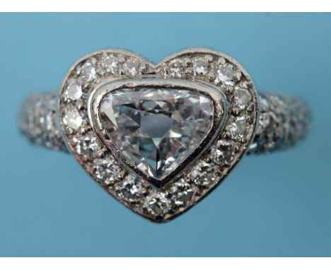A platinum and diamond heart shaped ring, the central trillion cut diamond approx. 1.0ct, within a surround of diamonds total