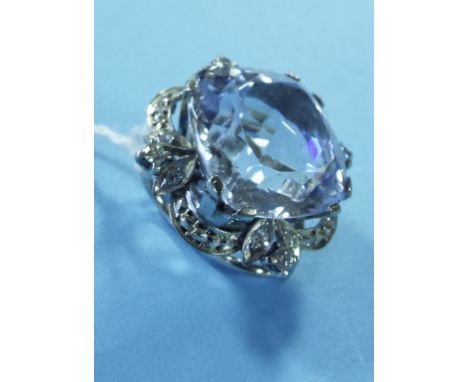 A white coloured metal clip, set a large spinel, within a diamond surround