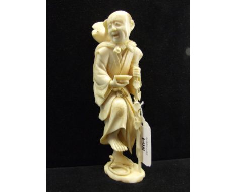 A Japanese carved ivory figure, in the form of a man with a bird on his back, holding a staff, and about to step on a snake, 