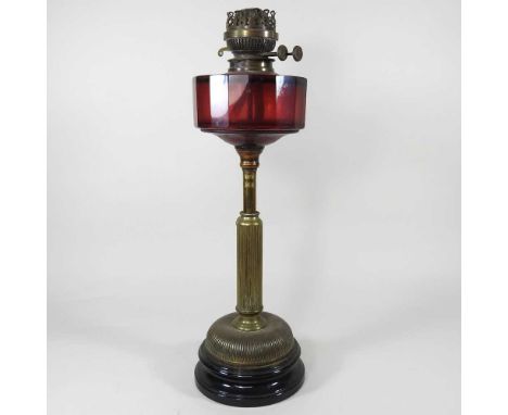 A 19th century brass adjustable oil lamp, with a fluted telescopic base and ruby glass font, 53cm highHeight adjusts ok. Both