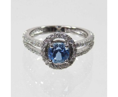 An 18 carat gold aquamarine and diamond halo ring, the central rose cut stone, within a diamond surround, flanked by twin dia