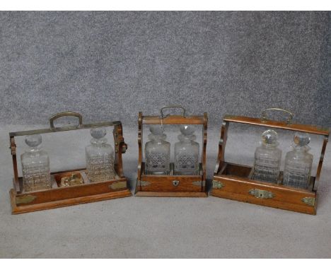 Three miscellaneous oak decanter tantaluses. (Two decanters missing) 