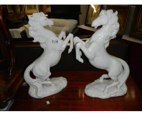 A pair of white ceramic rearing horses (one ear a/f)