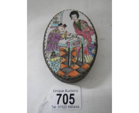 An oval pill box with enamel top.